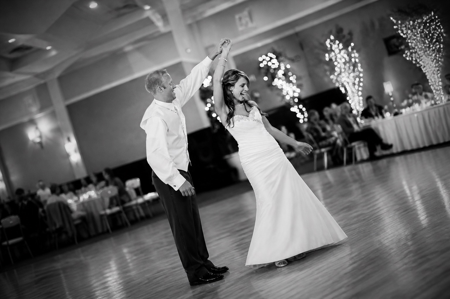 A bride smiling while dancing with a partner at her wedding reception